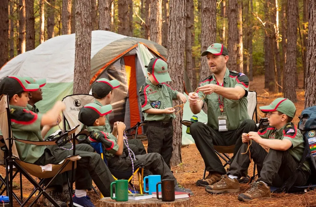 A Trailmen leader teaching knot-tying to a group of boys at a campsite
